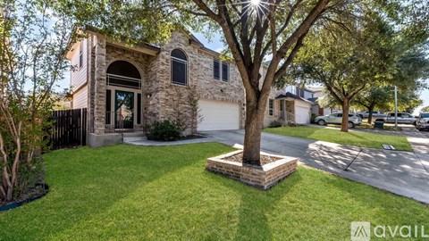 A house with a stone facade and a large tree in front.