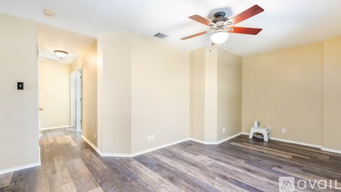 A room with a ceiling fan and wooden flooring.