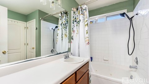 A bathroom with a white tub, sink, and shower curtain.