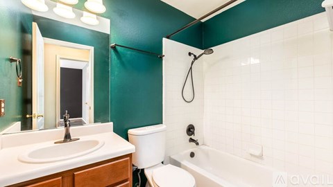 A bathroom with green walls and white fixtures.