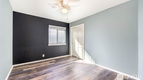 A room with a ceiling fan and a door.