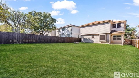 A house with a fence and a tree in front of it.