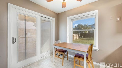 A room with a table and chairs in front of a window.