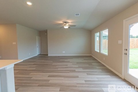 A spacious room with wooden flooring and a ceiling fan.