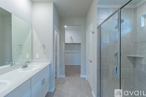 A bathroom with a walk-in shower and double sinks.
