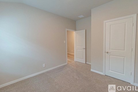 A room with a carpeted floor and two doors, one of which is open.