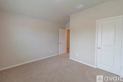 A room with a carpeted floor and two doors, one of which is open.
