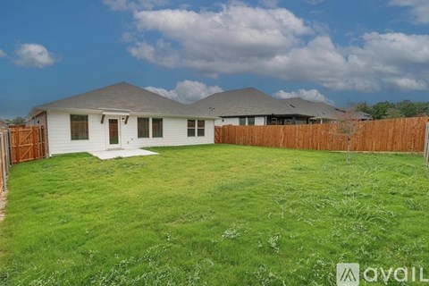 A house with a fence and a lawn in front of it.