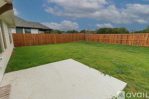 A backyard with a wooden fence and a concrete patio.
