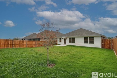 A house with a fence and a tree in the yard.