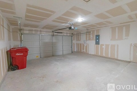A room with a red bin and a fan on the ceiling.