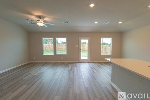 A spacious room with a ceiling fan and wooden flooring.