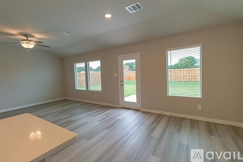 A spacious room with a ceiling fan and sliding glass doors.