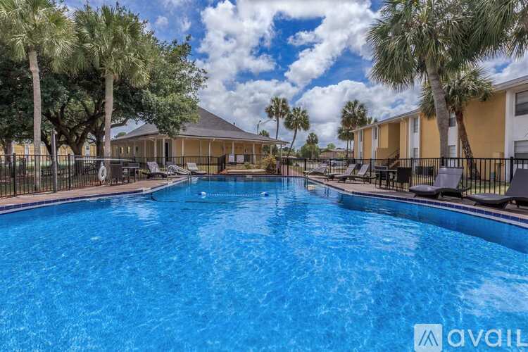 A large swimming pool surrounded by palm trees and lounge chairs.