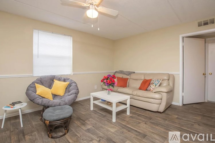 A living room with a grey chair, a white sofa, and a small table with a vase of flowers on it.