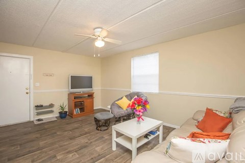 A living room with a white sofa, a wooden entertainment center, and a ceiling fan.