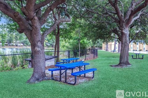 A blue picnic table is surrounded by trees in a grassy area.