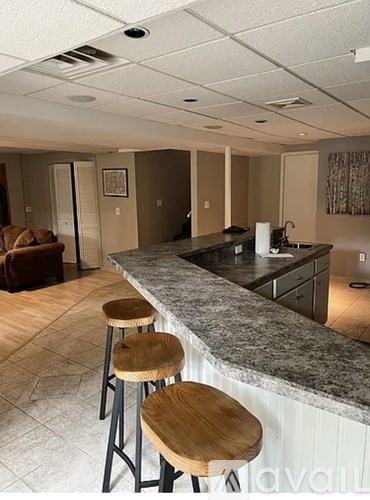 A kitchen with a bar area featuring a granite counter and wooden stools.