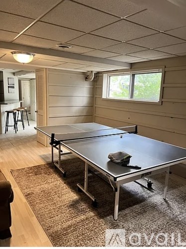 A ping pong table in a room with wooden walls and a rug on the floor.