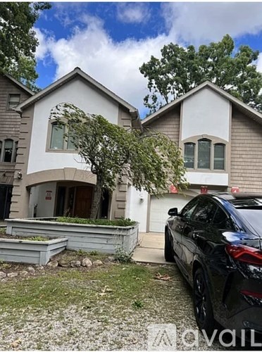 A black car is parked in front of a two-story house.