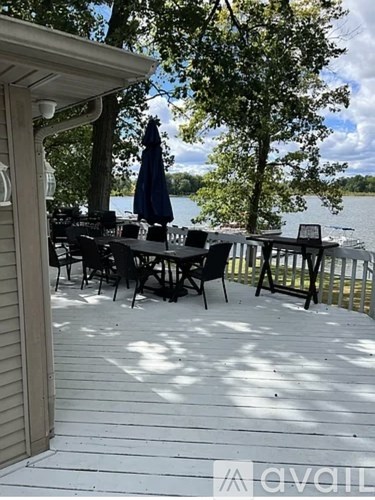 A table with chairs and an umbrella on a deck overlooking a lake.