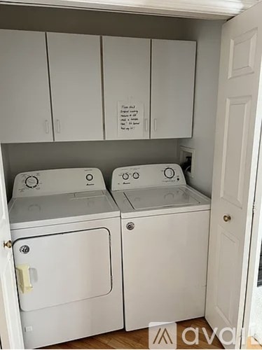 Two white washing machines in a small laundry room.
