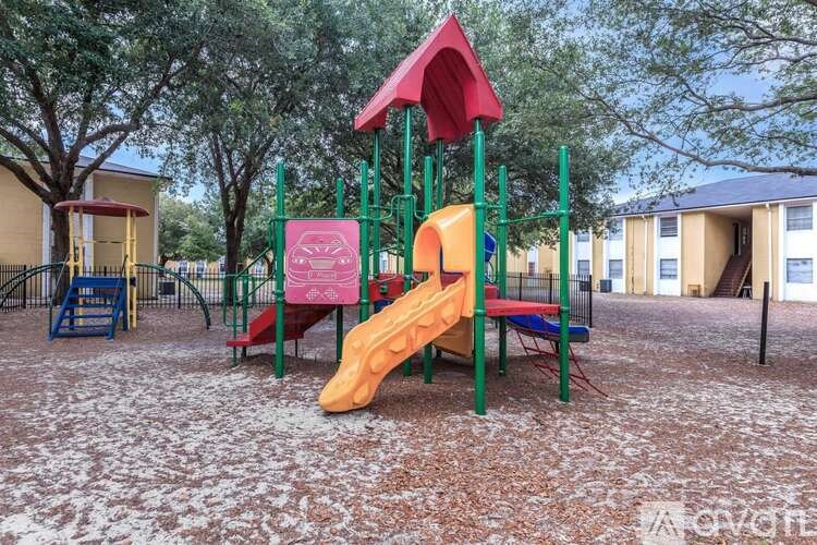 A playground with a red and green structure and a yellow slide.
