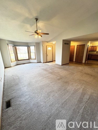 A spacious room with a ceiling fan and carpeted floor.