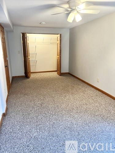 A room with a carpeted floor and a ceiling fan.
