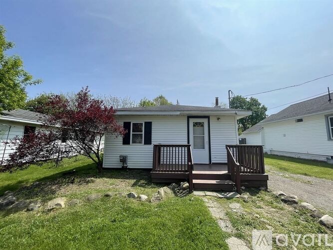 A small white house with a red tree in front.