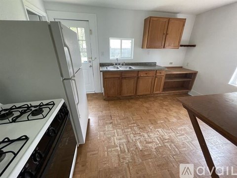 A kitchen with a white gas stove and wooden flooring.