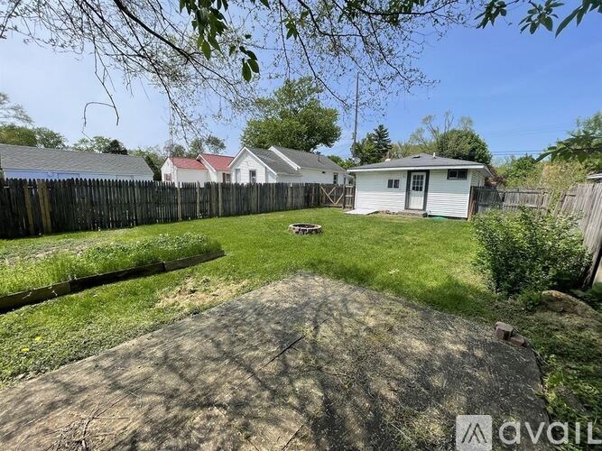 A backyard with a dirt path leading to a white house.