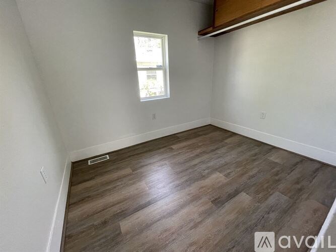 A room with wooden flooring and a window.