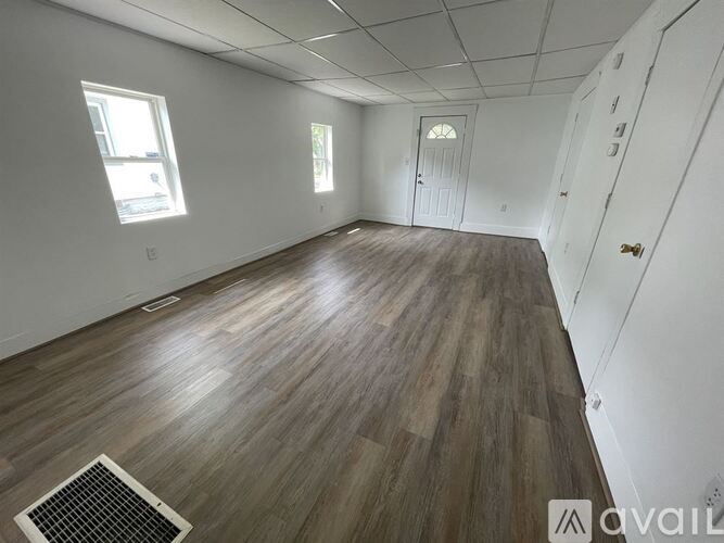 A room with wooden flooring and white walls is available for rent.