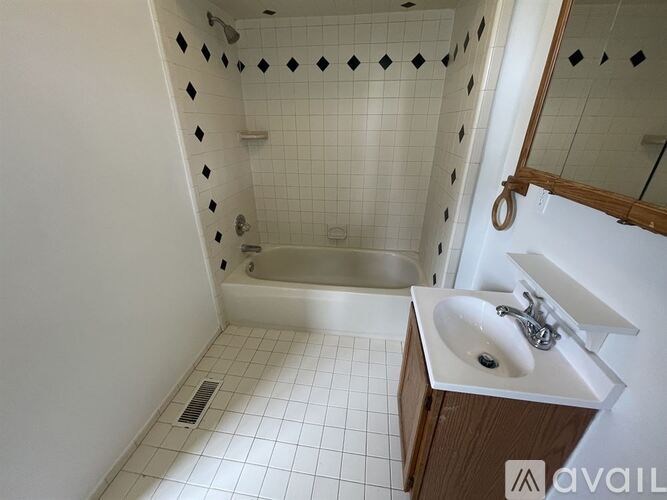A bathroom with a white tiled shower and a white sink.