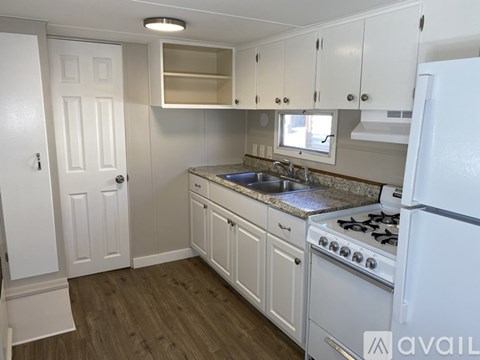 A kitchen with white cabinets and a white refrigerator.