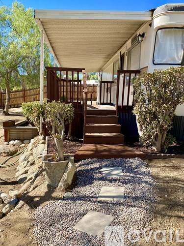 A patio area with a white awning and a gravel area in front of a house.
