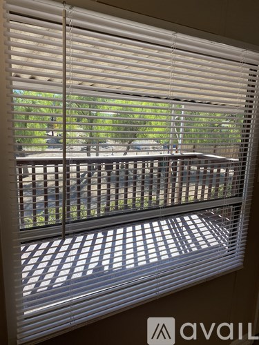 A window with white blinds partially open, letting in light.