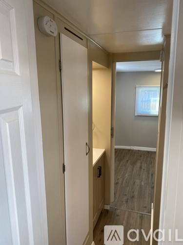 A hallway with a white door and a window in the background.
