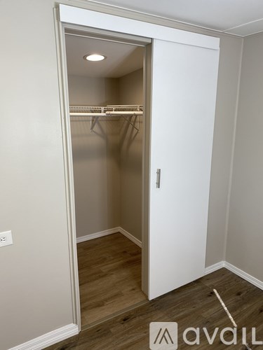 A white closet with a door open and clothes hanging on the rack.