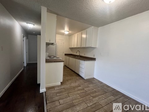 A kitchen with white cabinets and a wooden floor.