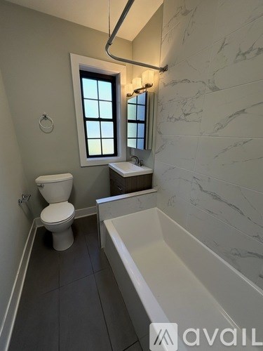 A bathroom with a toilet, tub, and window.
