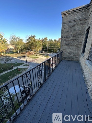 A balcony with a railing overlooks a park and a building.