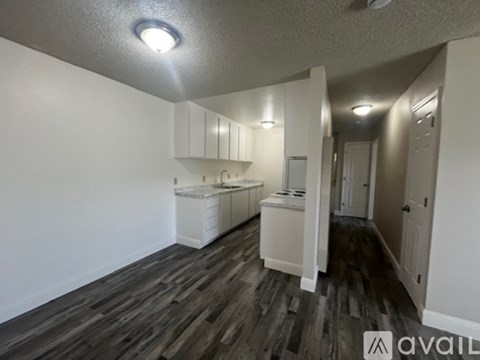 A kitchen area with white cabinets and a wooden floor.