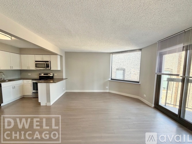 A spacious living room with a kitchen area in the background.
