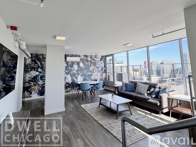A living room with a couch, chairs, and a coffee table with a view of the city.