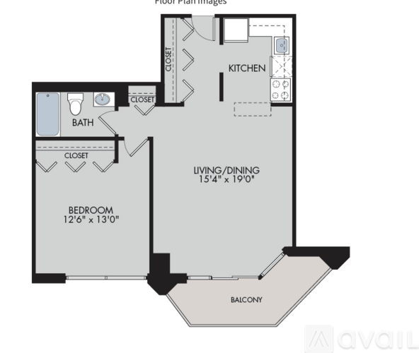A spacious room with wooden flooring and large windows overlooking a balcony.