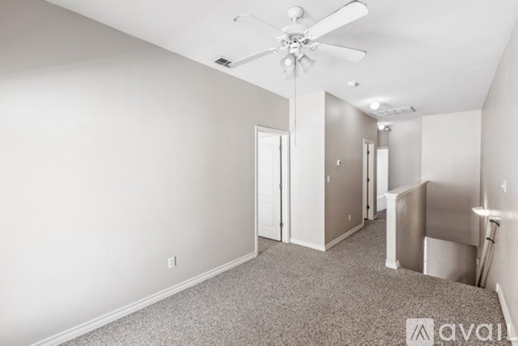 A spacious room with a ceiling fan and carpeted floor.