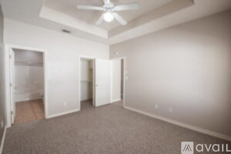 A room with a carpeted floor and a ceiling fan.