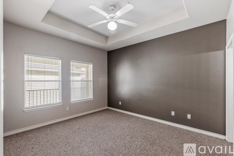 A room with a ceiling fan and two windows.